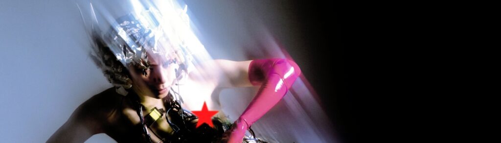Abstract portrait: person with metallic foil around the head, pink glove, motion blur, against a dark background, red star on chest.