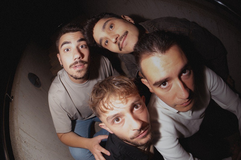 Four friends pose for a close-up, low-angle selfie, looking up at the camera.