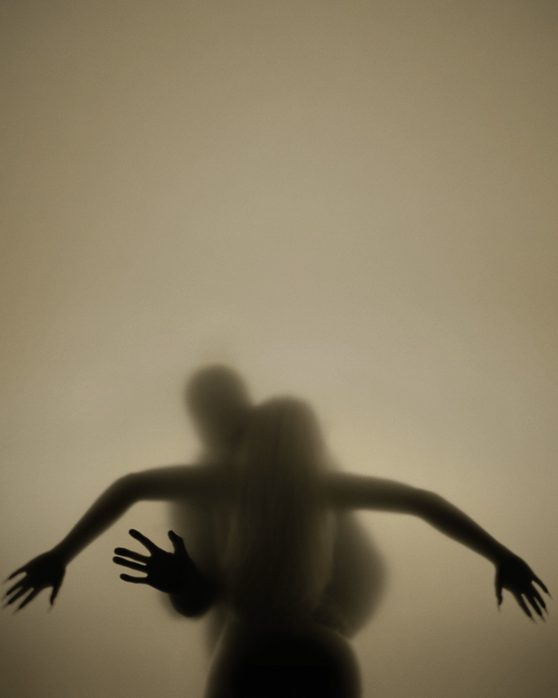 Two blurred figures behind frosted glass with arms outstretched, forming a silhouette.